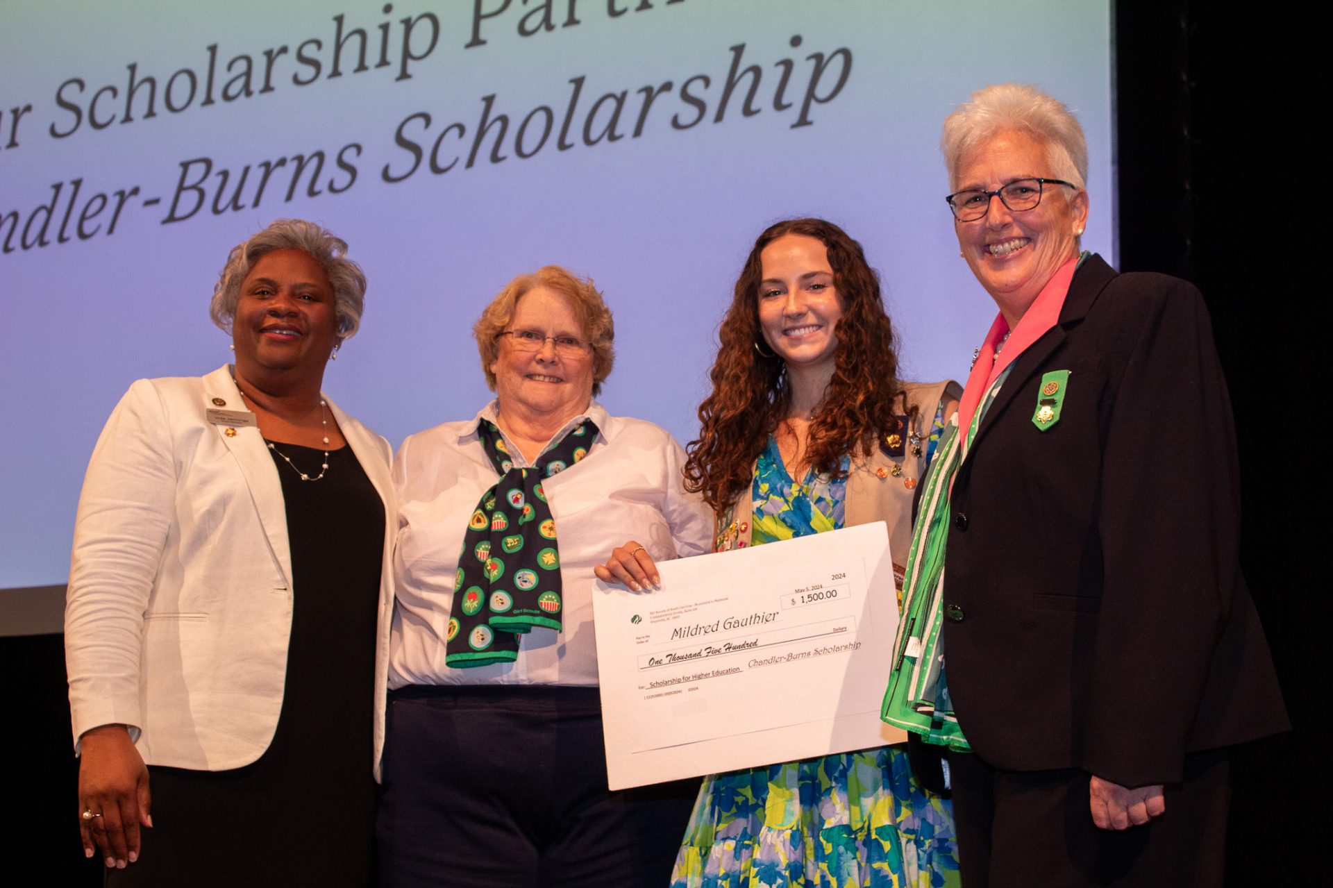 A girl scout poses onstage after earning Chandler-Burns Scholarship