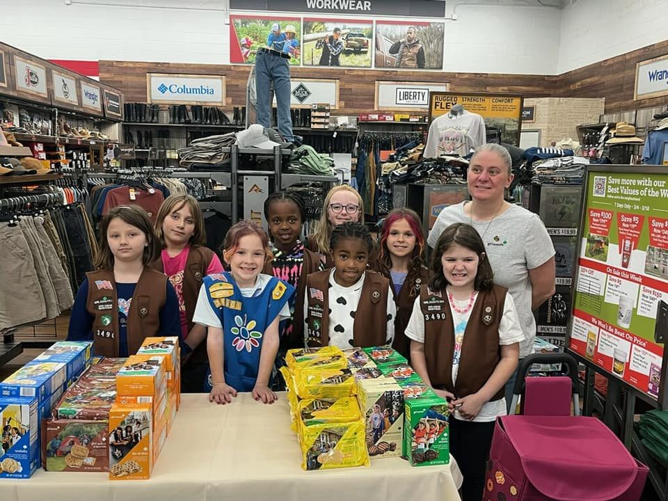 a troop sets up a cookie booth in an outdoor clothing store