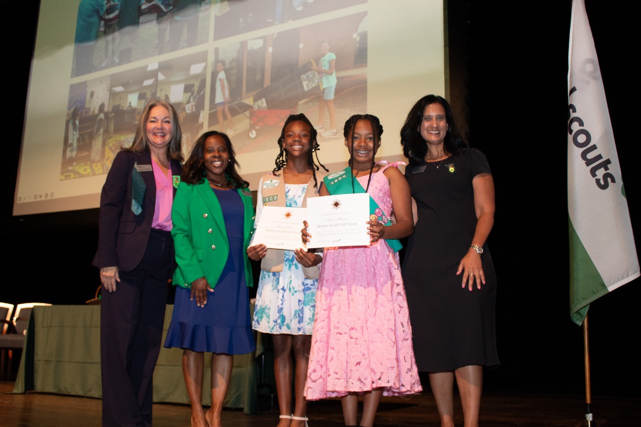 Two Bronze Award Girl Scouts pose with troop leader and council representatives