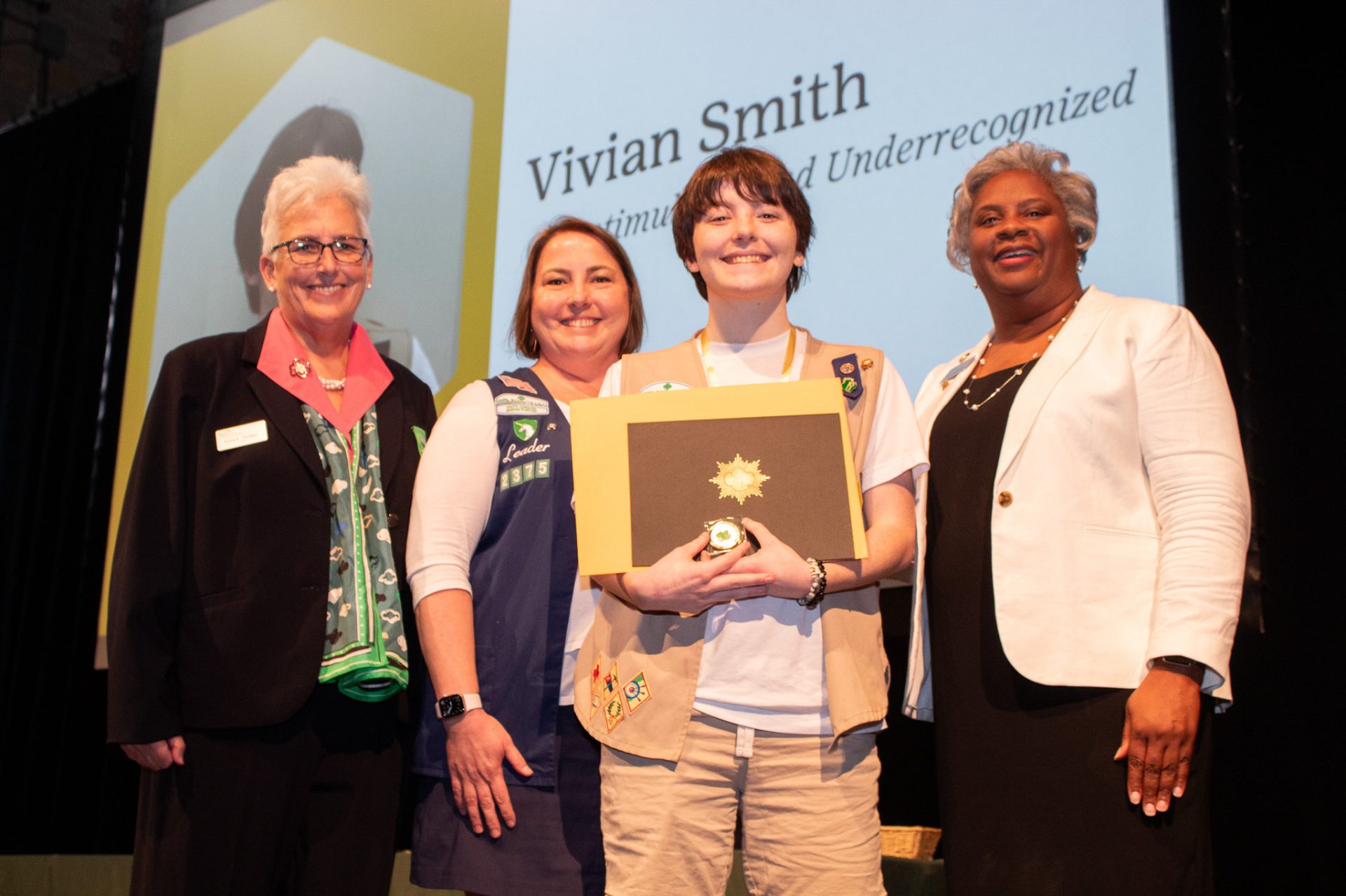 Gold Award Girl Scout and her family pose with council staff during award ceremony