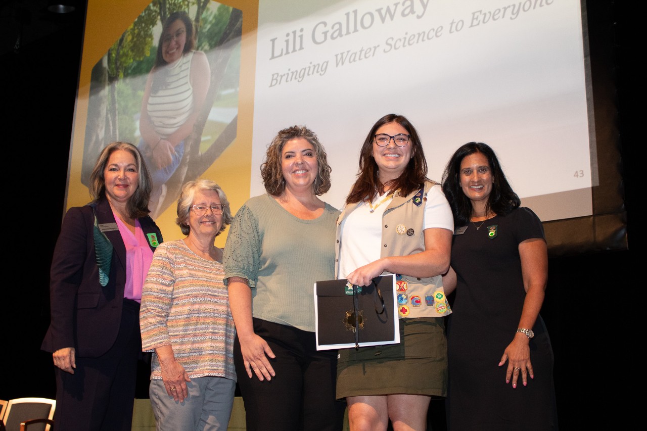 Gold Award Girl Scout and her family pose with council staff during award ceremony