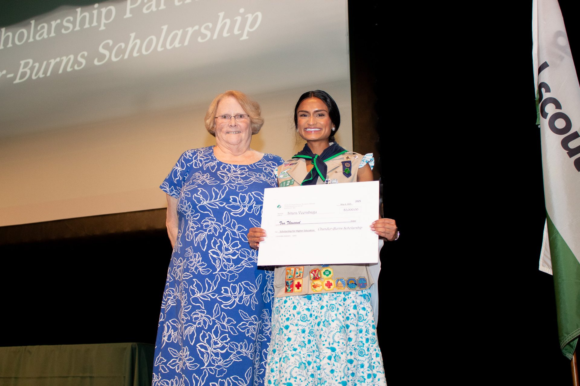 A girl scout poses onstage after earning Chandler-Burns Scholarship