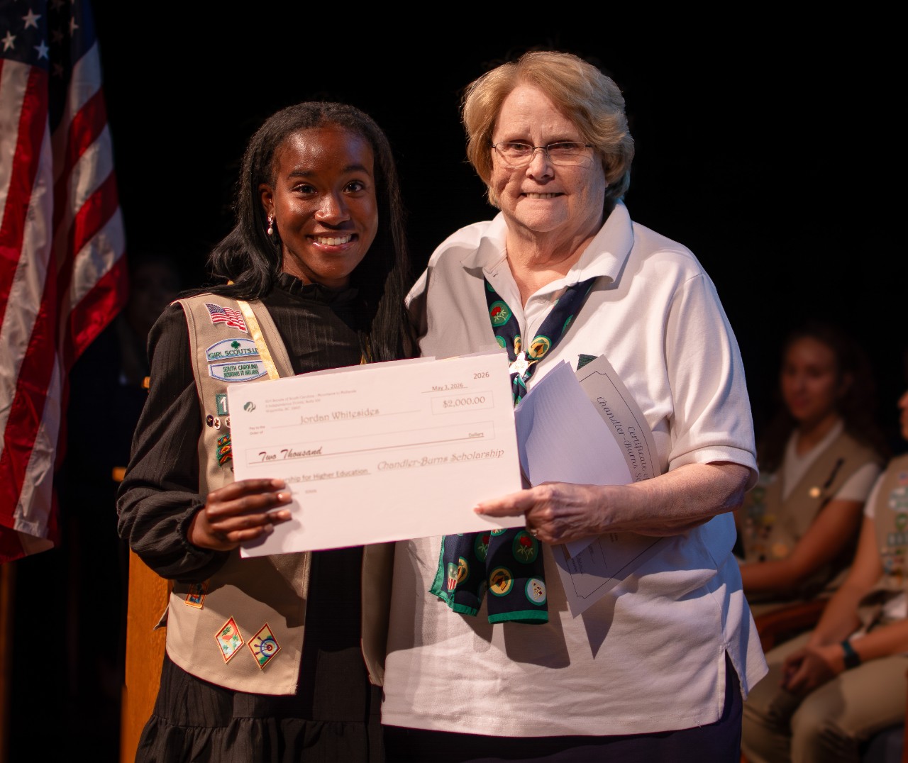 A girl scout poses onstage after earning Chandler-Burns Scholarship