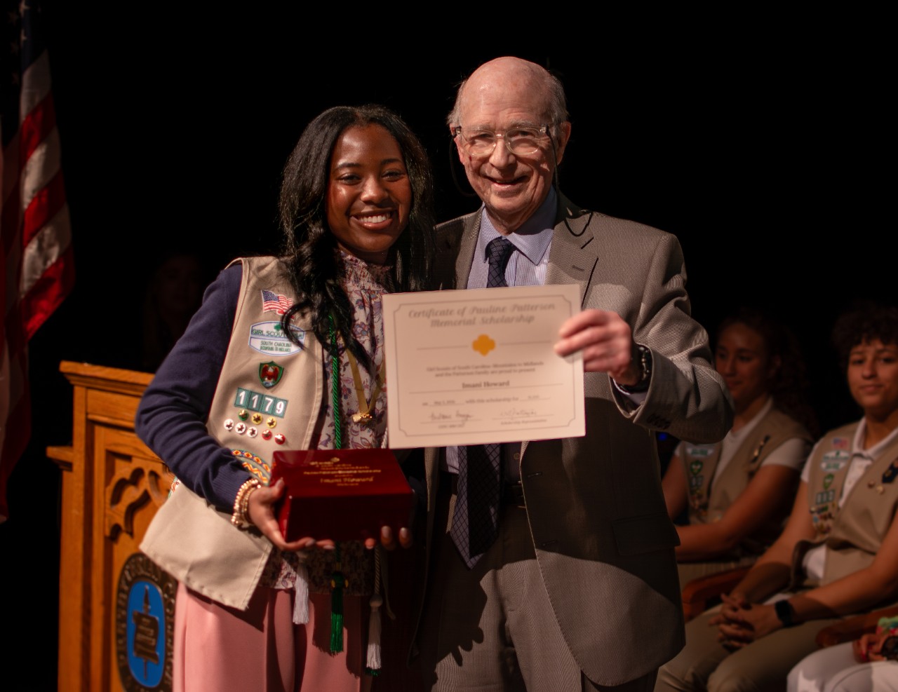 a girl scout poses with Mr. Patterson after earning the scholarship