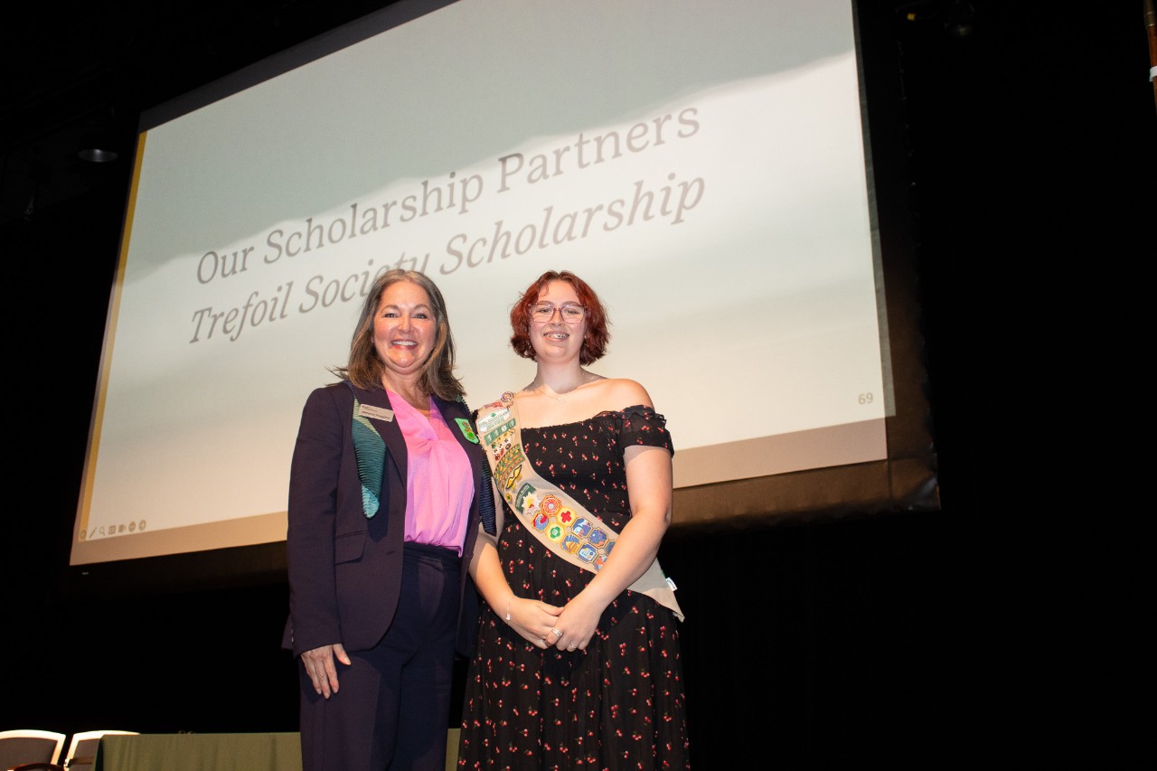 a girl scout poses with CEO Melanie Huggins after earning the Trefoil Society Scholarship