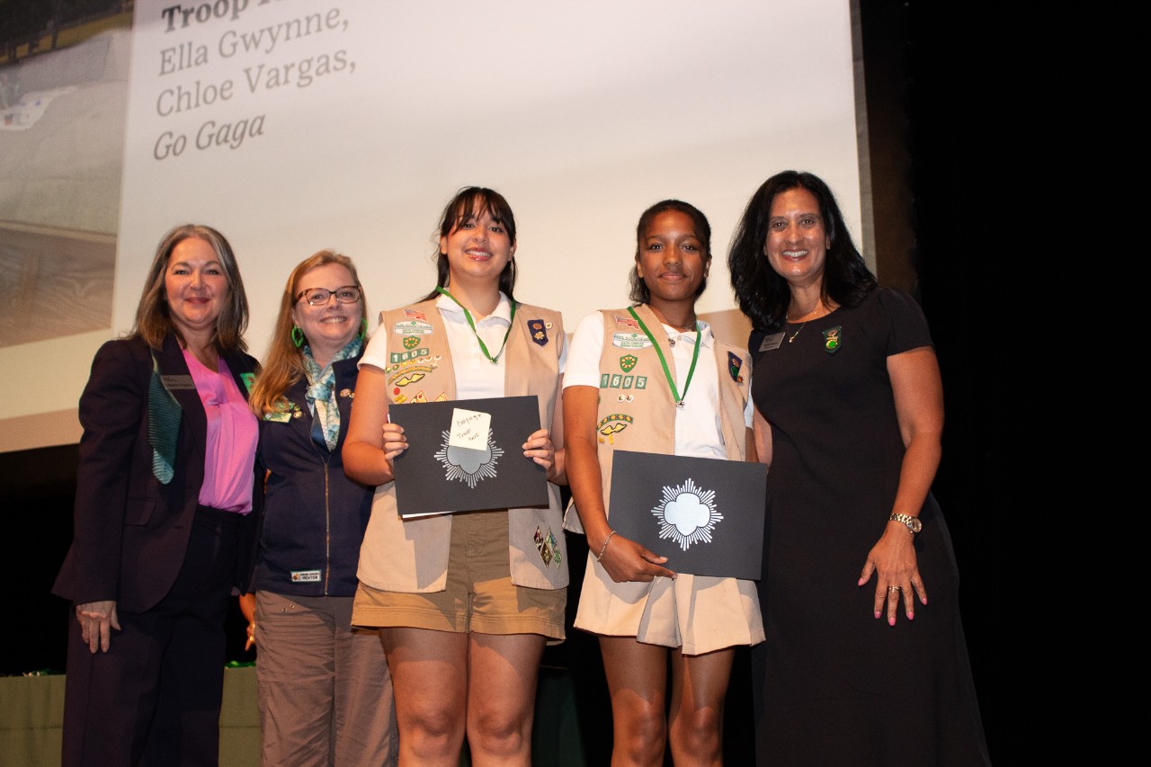 two Silver Award Girl Scouts pose with troop leader and council representatives at ceremony