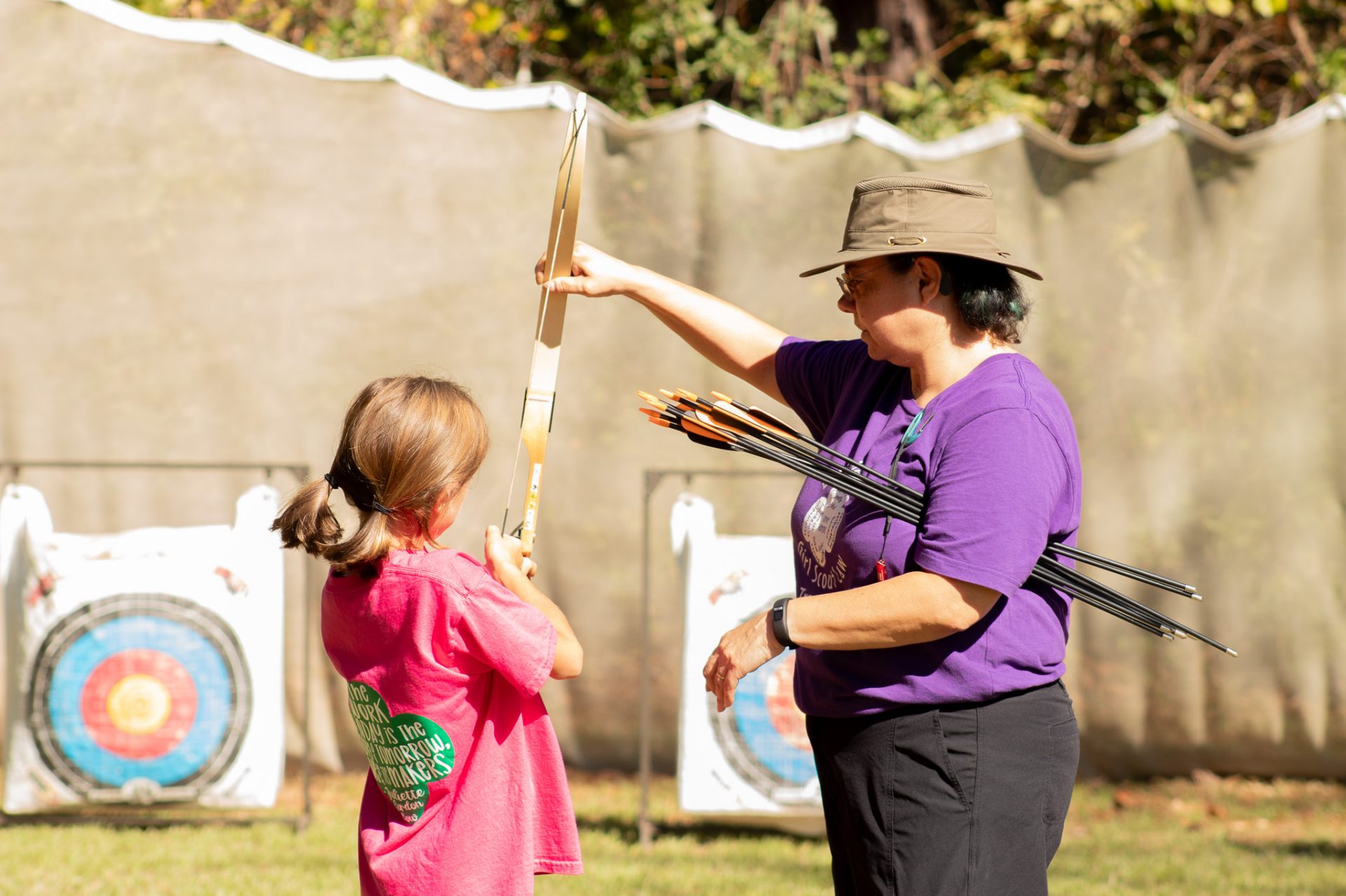  A volunteer with blue hair and a teal hoodie holds a fuel canister in front other volunteers at a outdoor cooking training. 